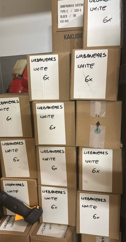 Stack of cardboard boxes labeled with 'Urbanears White' on a shelf.