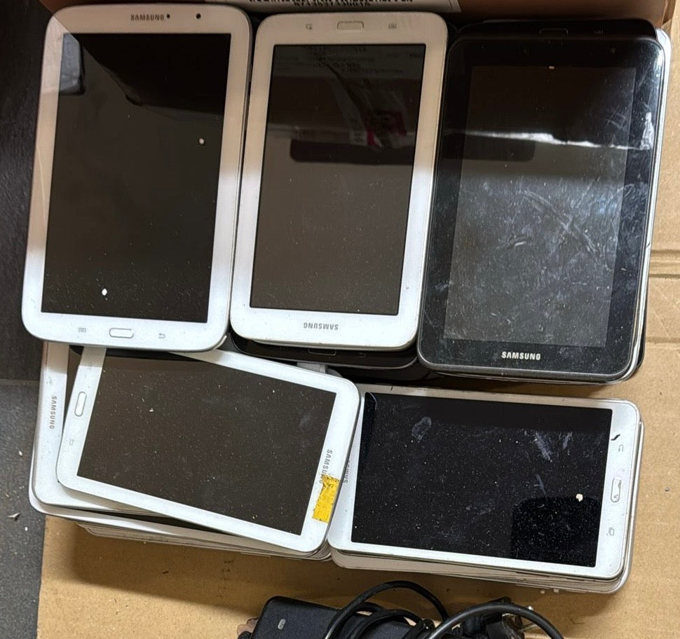 Collection of Samsung tablets with screens damaged on a cardboard box.