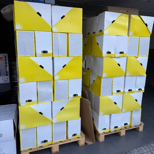 Stacks of white boxes with yellow labels on a pallet outdoors.